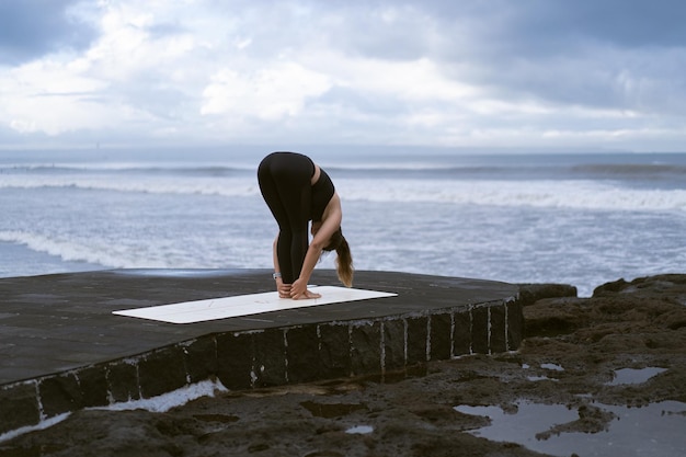 Young woman practice yoga on a beautiful beach at sunrise. Blue sky, ocean, waves, proximity to nature, unity with nature.