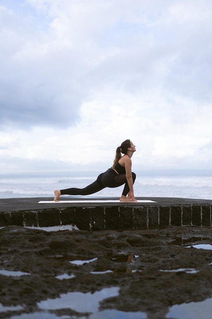 Young woman practice yoga on a beautiful beach at sunrise. Blue sky, ocean, waves, proximity to nature, unity with nature.