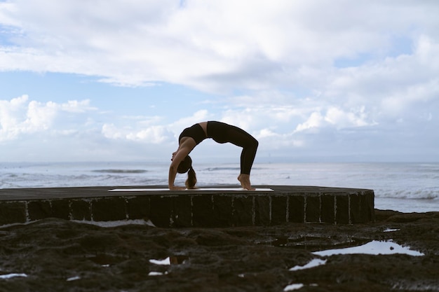 Young woman practice yoga on a beautiful beach at sunrise. Blue sky, ocean, waves, proximity to nature, unity with nature.