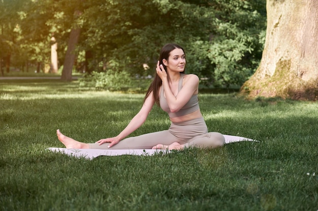 A young woman practices yoga in a city park on a warm summer day