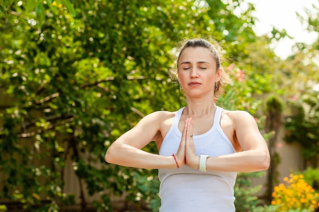 Young woman practices yoga in the garden