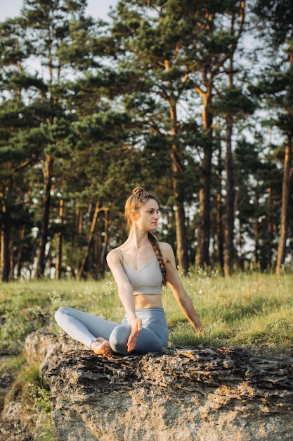 Photo a young woman practices yoga and meditates in the mountains at sunset peace and unity with nature