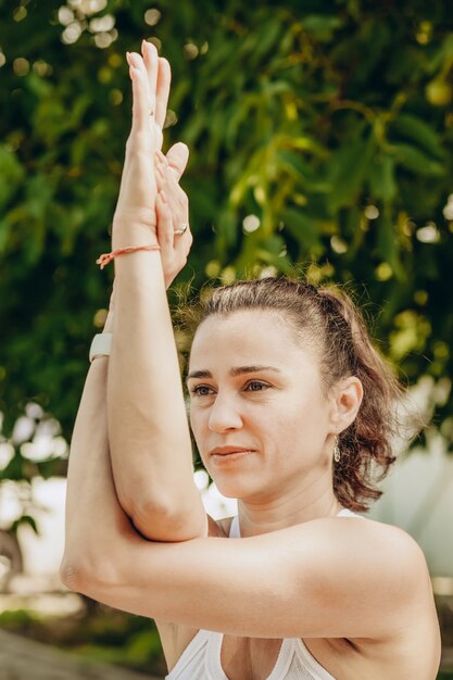 Young woman practices yoga in the summer garden Garudasana or Eagle Pose