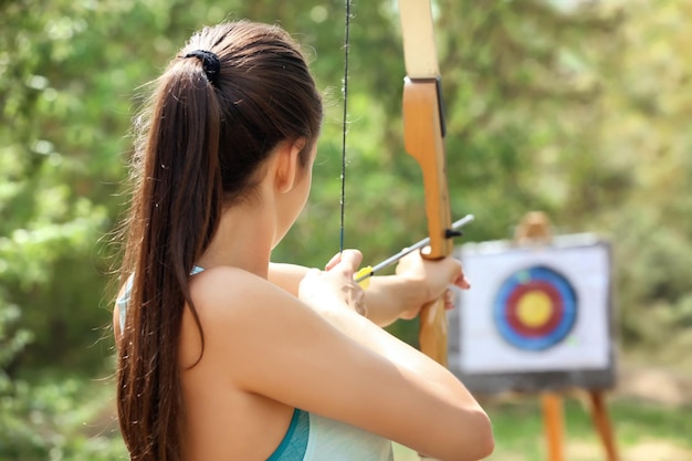 Young woman practicing archery outdoors