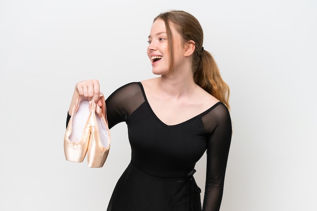 Young woman practicing ballet isolated on white background laughing in lateral position