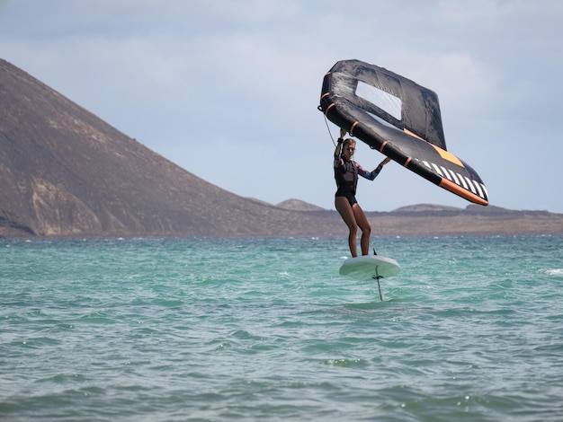 Young woman practicing wingfoil on hydrofoil surfboard