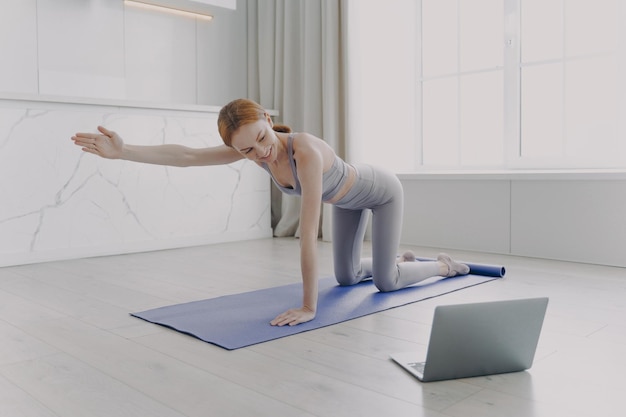 Young woman practicing yoga by video tutorial Posture exercise Home classes on quarantine