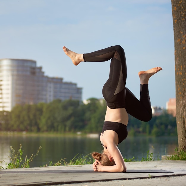 Young woman practicing yoga at city lake