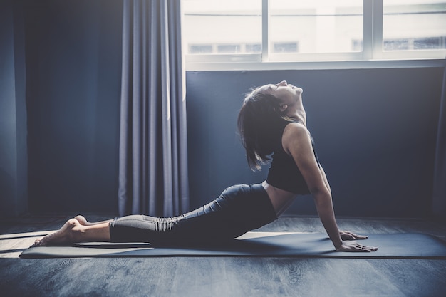 Young woman practicing yoga in class; Beautiful girl feeling Calmness and relax in yoga class