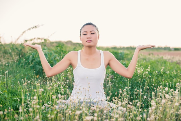 Young woman practicing yoga on grassy field