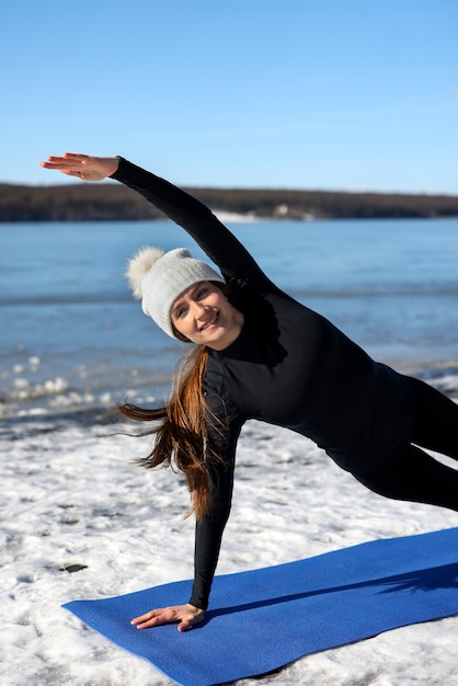 Young woman practicing yoga outdoors during winter on the beach