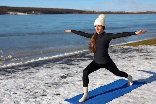 Young woman practicing yoga outdoors during winter on the beach