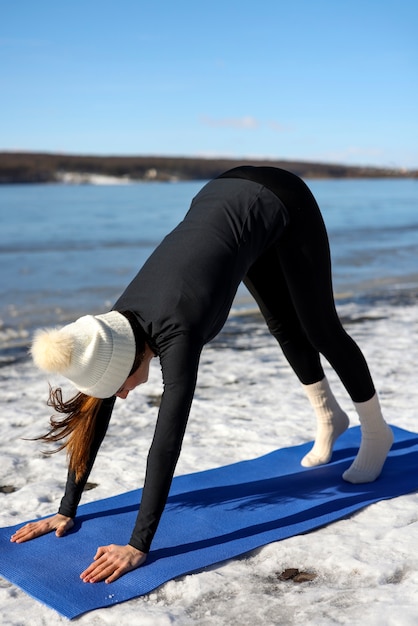 Young woman practicing yoga outdoors during winter on the beach