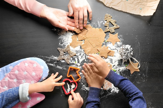 Photo young woman preparing christmas cookies with little children at table