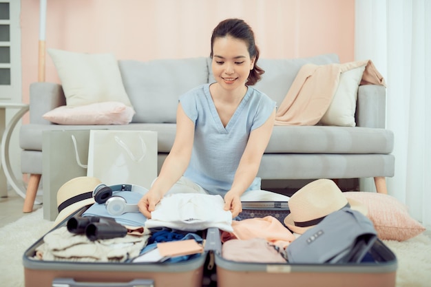 Young woman preparing and packing clothes into suitcase on a bed at home holiday travel concept