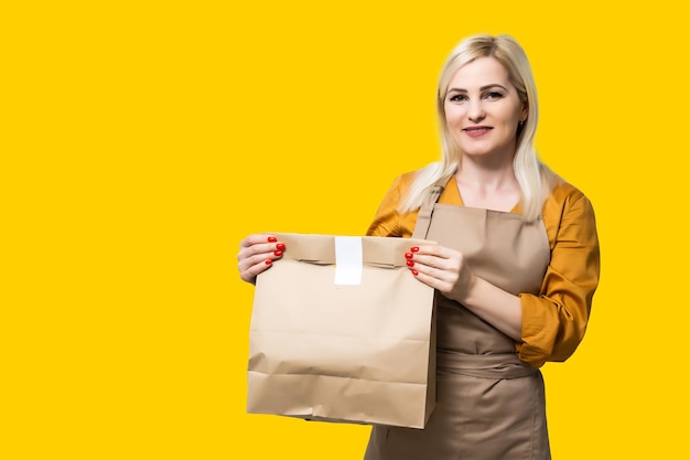 Young woman preparing takeaway organic food inside plastic free restaurant during Coronavirus outbreak time - Worker inside kitchen cooking food for online delivery service.