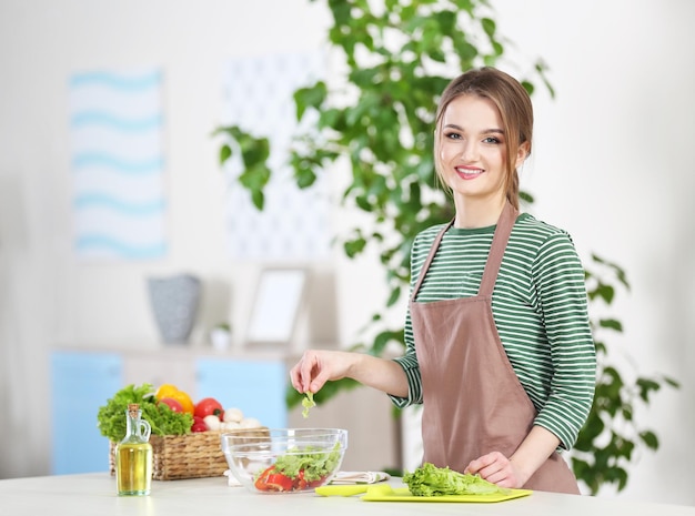 Young woman preparing vegetable salad in the kitchen