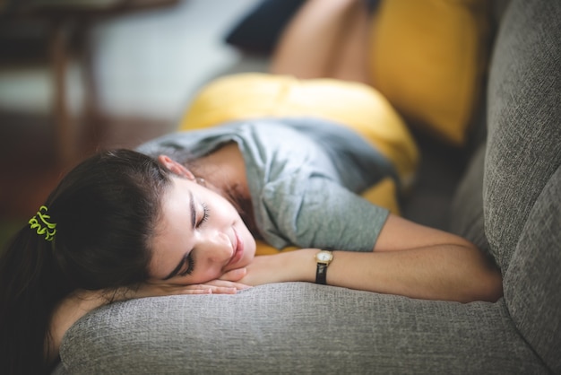 Young woman pretty girl living and resting peace on cozy sofa, couch enjoying, lying relax at indoor apartment room, smile comfort