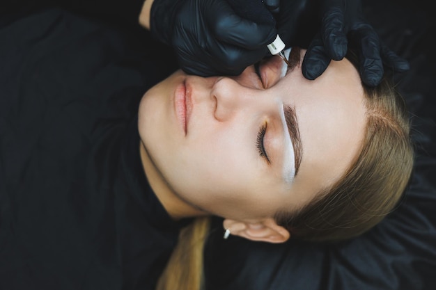 Young woman during professional eyebrow mapping procedure before permanent makeup