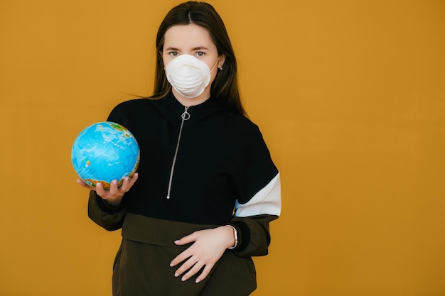 Young woman in protective face mask holding globe