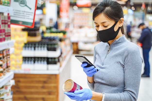 Young woman in protective mask and gloves scanning a barcode