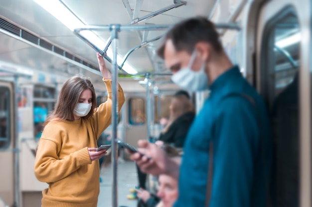 Young woman in a protective mask standing in a subway car. coronavirus in the city