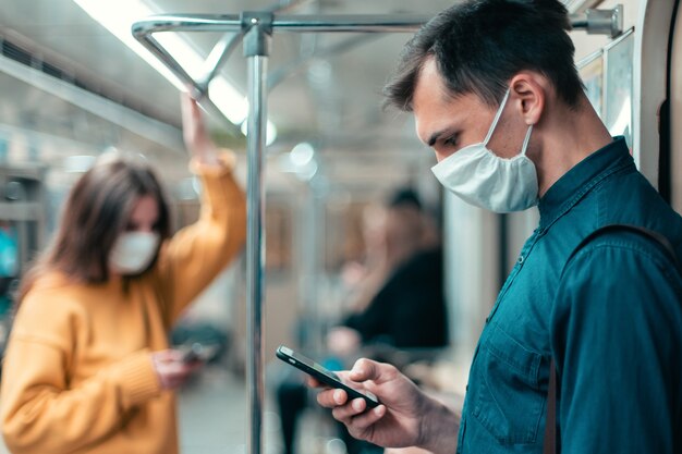 Young woman in a protective mask standing in a subway car.