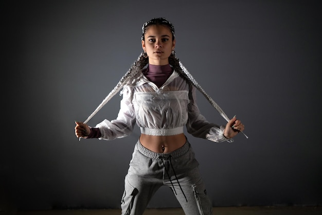 Young woman pulling her braids while looking at camera in a studio shot