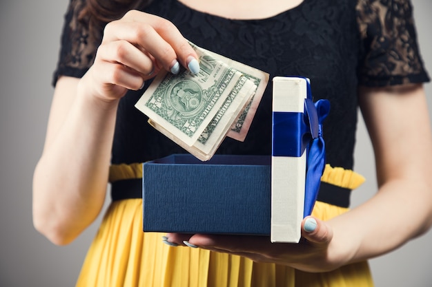 Young woman pulls money out of a gift box