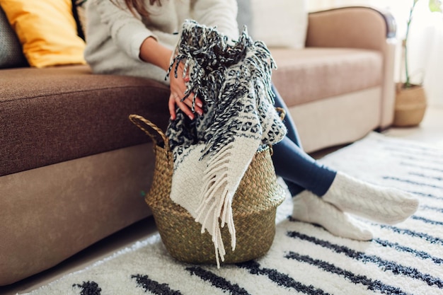 Young woman puts blanket in straw basket interior decor of living room