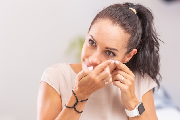 A young woman puts contact lenses in her eyes.