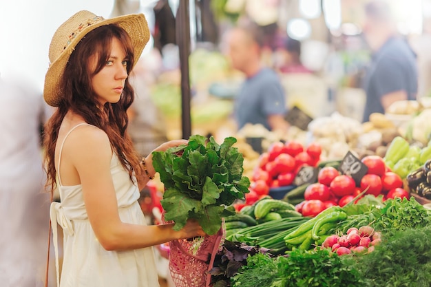 Young Woman puts fruits and vegetables in cotton produce bag at food market. Reusable eco bag for shopping. Zero waste concept.