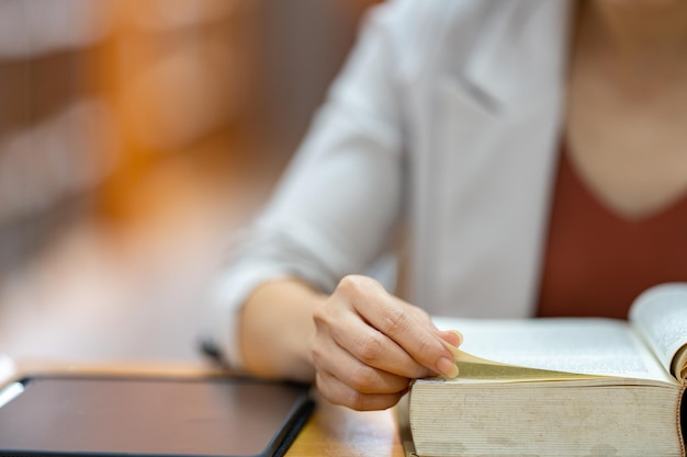 Young woman reading a book in library at university