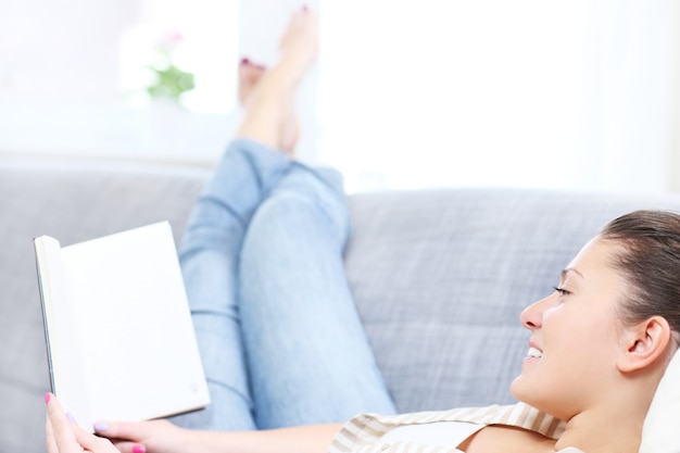 a young woman reading a book on a sofa