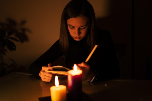 Young woman reading by candlelight. Blackout concept, power cut