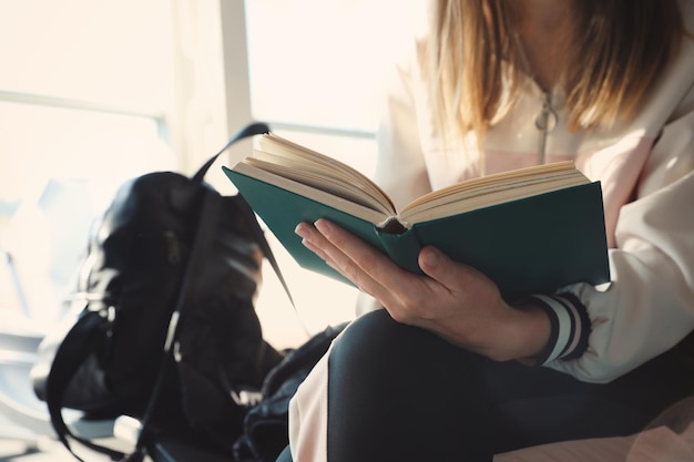 Young woman reading hardcover book indoors closeup