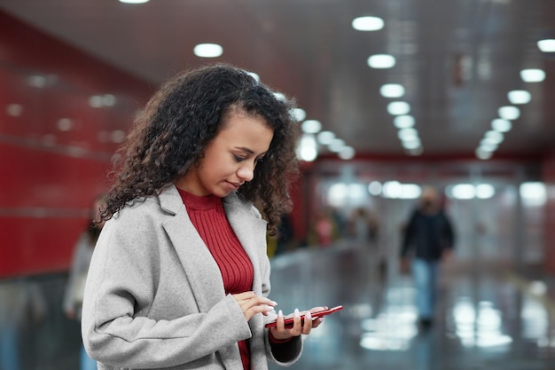 Young woman reading a text message going up the escalator in the subway