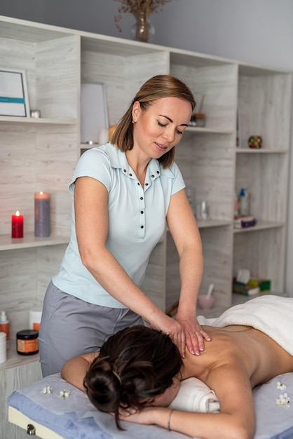 Young woman receive manual relax massage on neck lying on table in spa salon