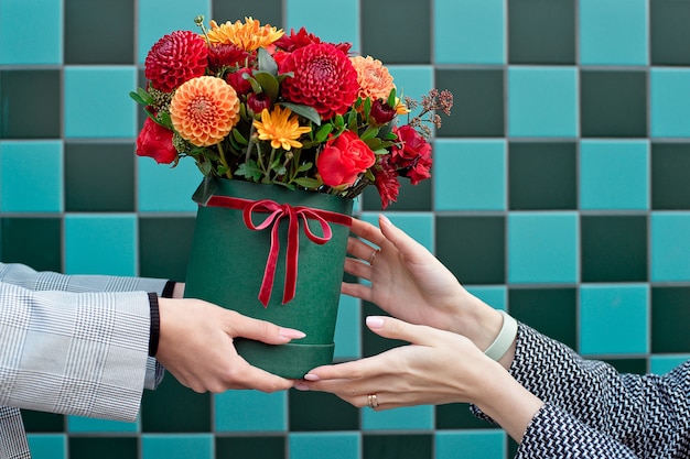 Young woman receiving beautiful peony flowers from delivery woman.