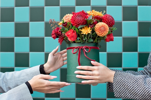 Young woman receiving beautiful peony flowers from delivery woman.