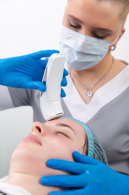 Young woman receiving electric galvanic antiaging face spa massage at beauty salon