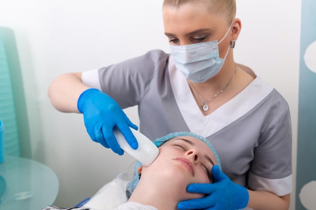 Young woman receiving electric galvanic antiaging face spa massage at beauty salon