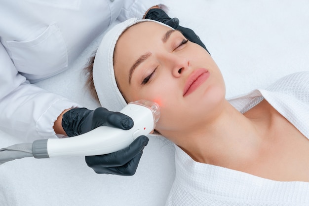 Young woman receiving laser treatment in cosmetology clinic