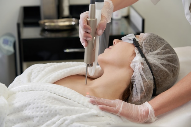 Young woman receiving laser treatment in cosmetology clinic