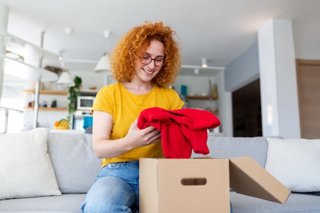 Young woman receiving parcel at home Holiday shopping online and unpacking cardboard box Delivery service during covid quarantine Happy girl getting gift Lifestyle moment