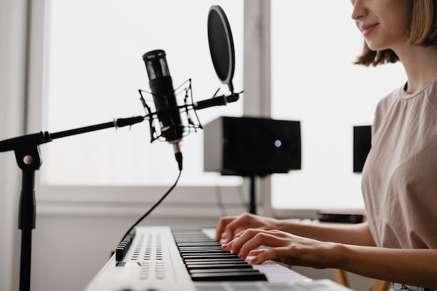 Young woman recording a song playing piano and singing at home