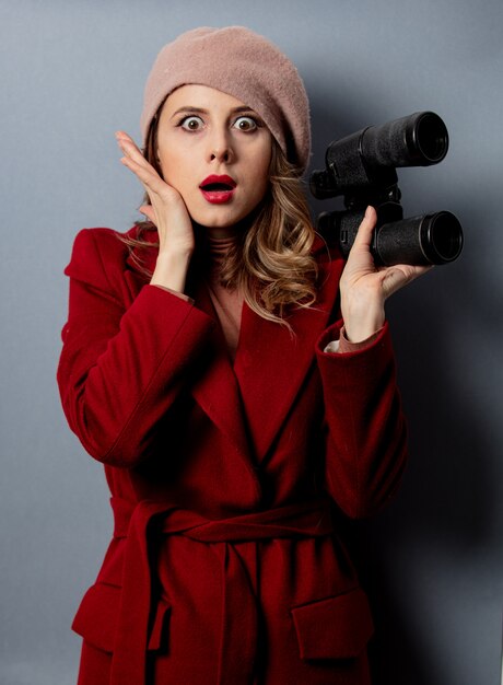 Photo young woman in red coat with binoculars