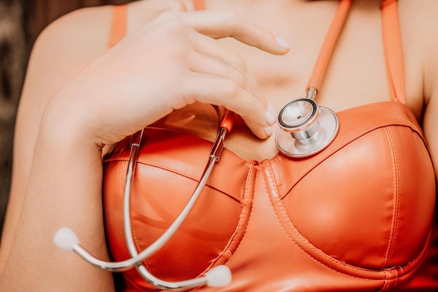 Young woman in red corset and black leather pants with a phonendoscope sexy brunette nurse in red