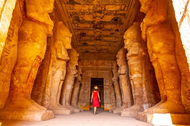 A young woman in a red dress at the Abu Simbel Temple next to the sculptures