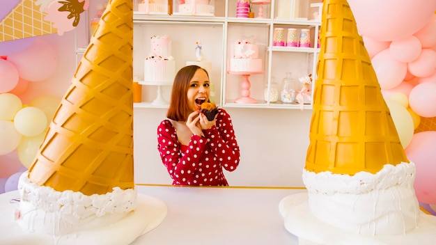 Young woman in red dress with short hair eating muffin in confectionery